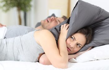 Woman with Pillow Over Her Head Due to Partner's Snoring